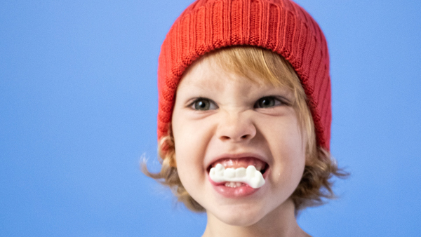 Ein Kind zeigt die Zähne und den Kaugummi